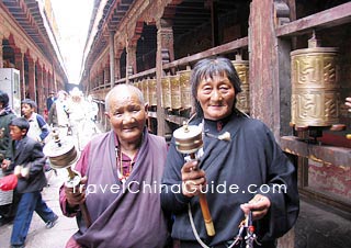 Two Tibetan elders hold the pray wheels for good fortune.