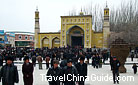 Groups of visitors are coming into and going out of the Id Kah Mosque.