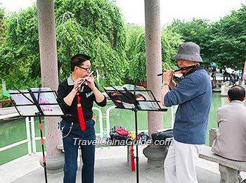 Two Chinese People playing a bamboo flute in the park